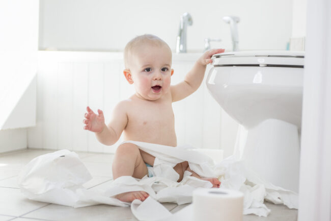 Adorable baby boy playing with toilet paper